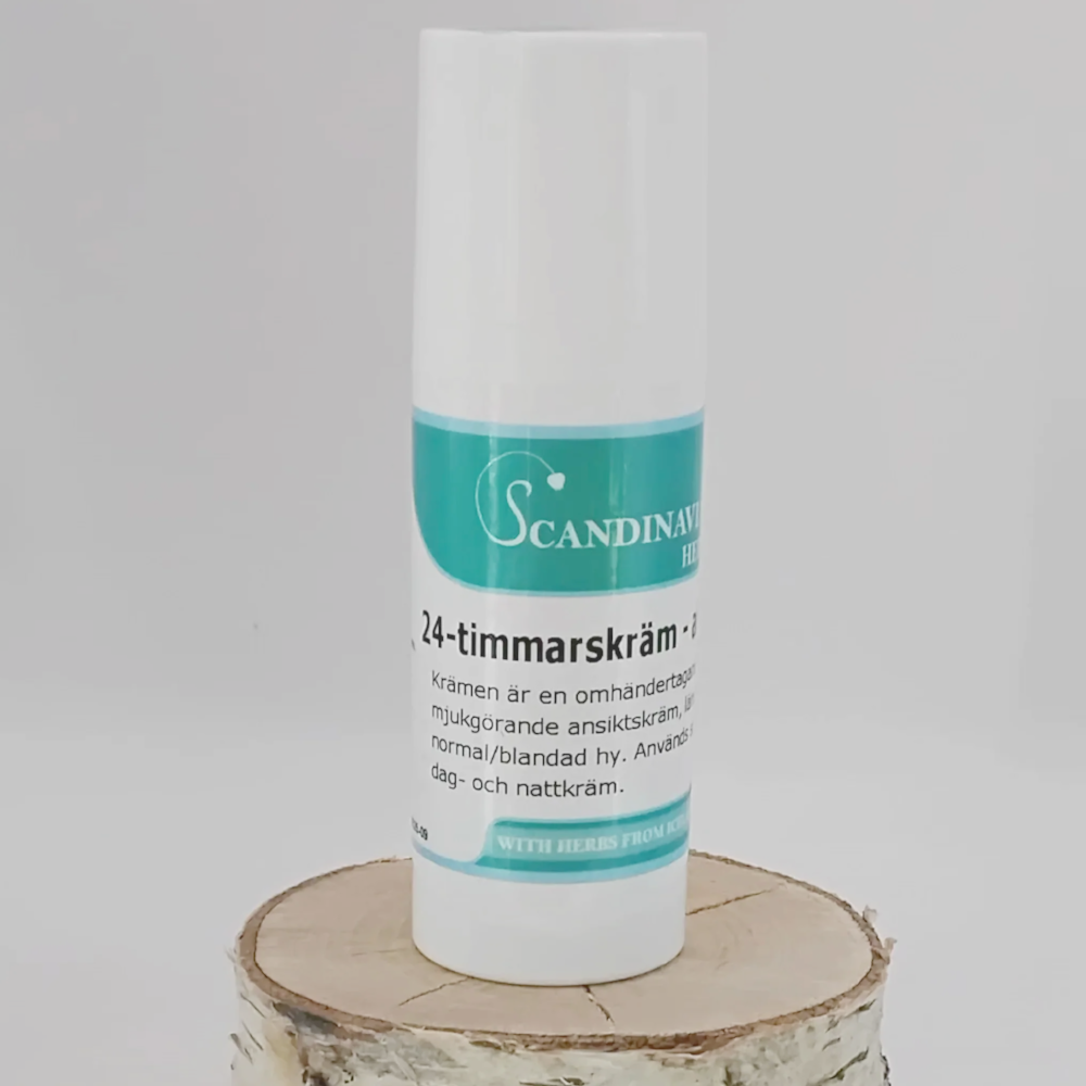 A white cylindrical bottle of Scandinavian Herbs 24-timmars kräm - för yngre hud rests on a wooden slice. The green and white label, in Swedish, promises läkande effekter. Its against a plain, light backdrop suitable for normal till fet hy.