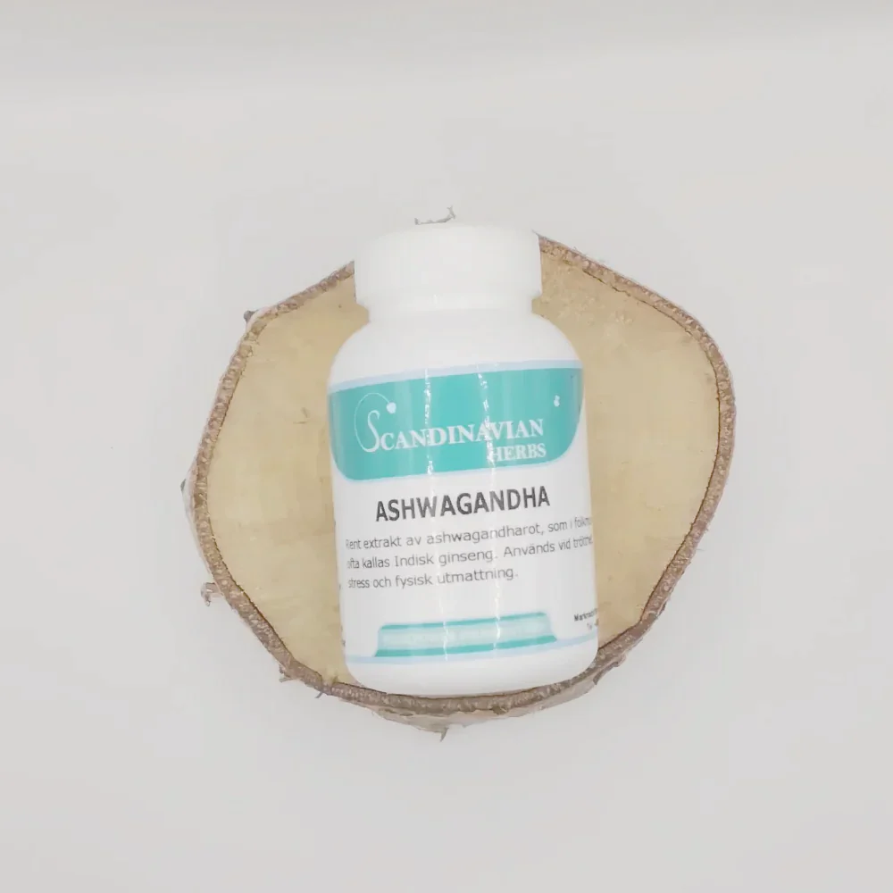 A white bottle labeled Ashwagandha - bra vid stress och trötthet from Scandinavian Herbs features Swedish text and rests on a round wooden slice with bark edges. Highlighting Ayurvedas power, it stands against a plain white background, emphasizing the benefits of Withania Somnifera.