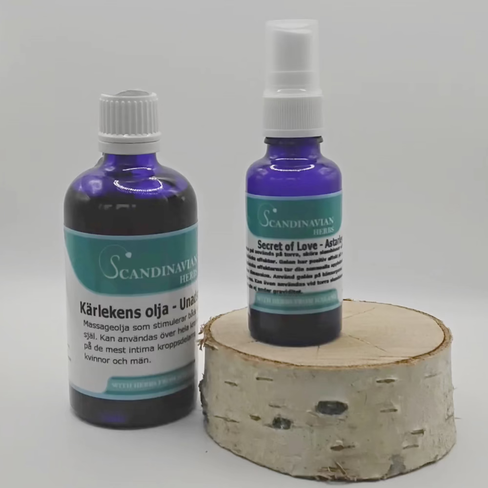 On a birch wood base, two blue glass bottles showcase Scandinavian design by Scandinavian Herbs. The left bottle, labeled Kärlekens olja, offers kärleksolja with afrodisiaka effekter, while the right, smaller bottle branded Secret of Love features a spray nozzle.